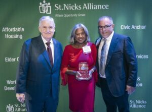 Honoree proudly holding the award, posing with others and smiling.